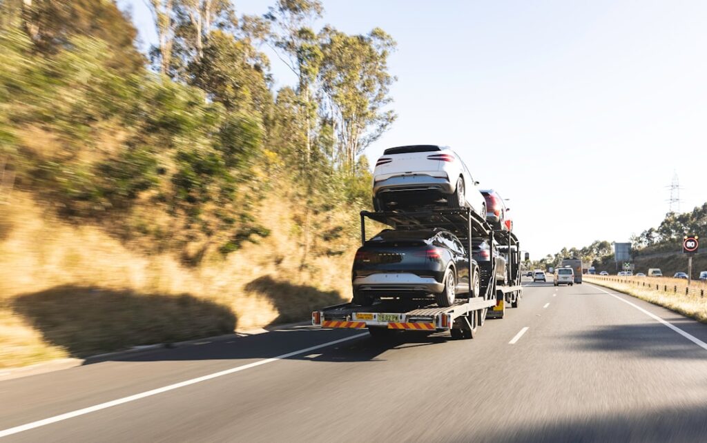 A car being loaded onto a multi-vehicle auto transport truck on a suburban street.