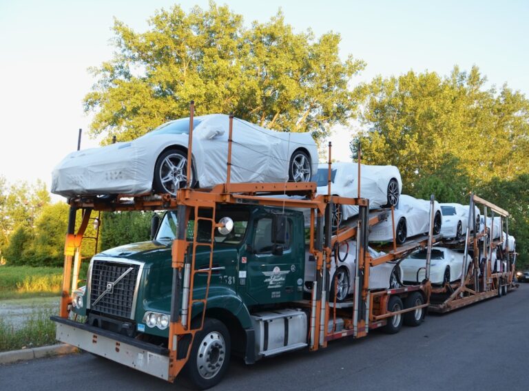 A car being inspected and loaded onto a large transport truck on a quiet residential street.